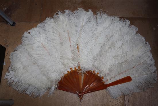 Two white ostrich feather fans, one with gold-monogrammed blond faux-tortoiseshell guard sticks and handle,